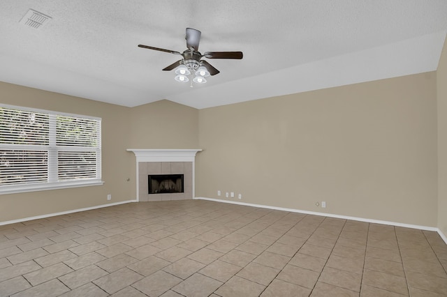 unfurnished living room featuring ceiling fan, a textured ceiling, a fireplace, and light tile patterned floors