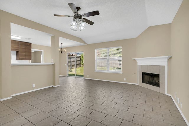 4629 Grant Park Ave, Fort Worth, TX 76137 - unfurnished living room with baseboards, a tiled fireplace, a textured ceiling, vaulted ceiling, and ceiling fan with notable chandelier
