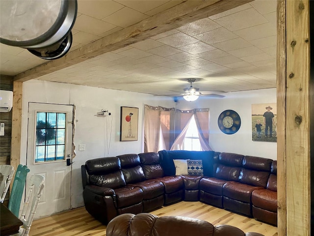 living room featuring ceiling fan, beam ceiling, light hardwood / wood-style floors, and a wall unit AC