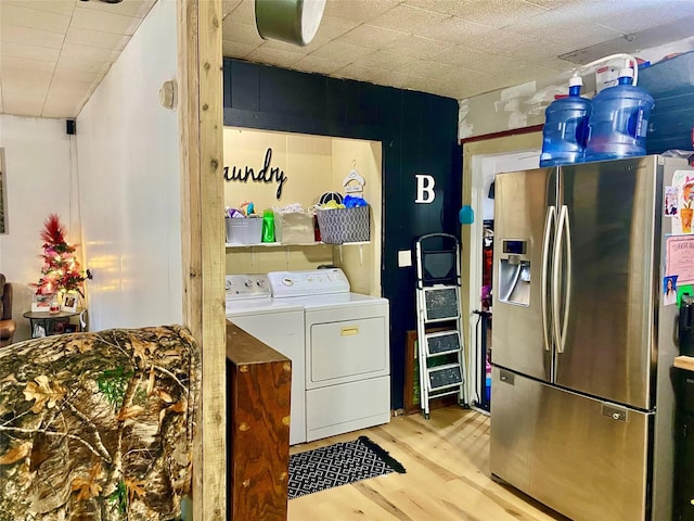 clothes washing area featuring washing machine and clothes dryer and light wood-type flooring