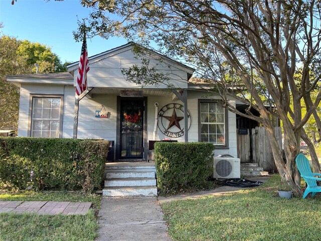 view of front of home with ac unit and a front lawn