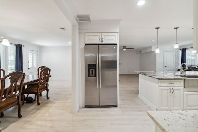 kitchen with light stone counters, a kitchen island with sink, ceiling fan, sink, and light hardwood / wood-style flooring