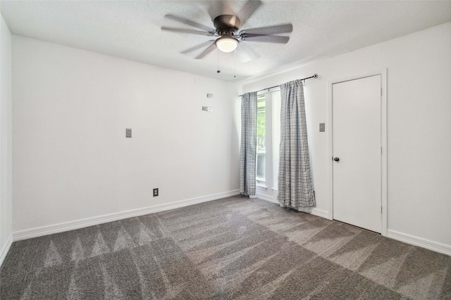 spare room featuring ceiling fan and dark colored carpet