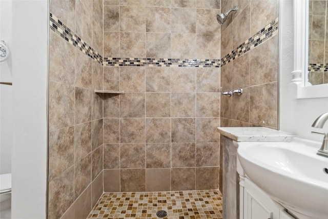 bathroom with a tile shower and vanity