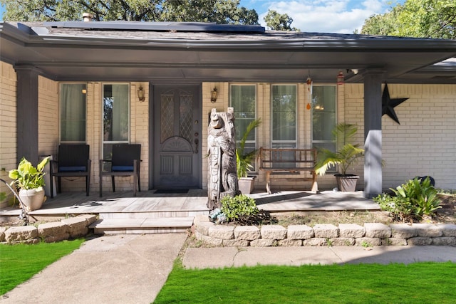 view of exterior entry with covered porch and solar panels