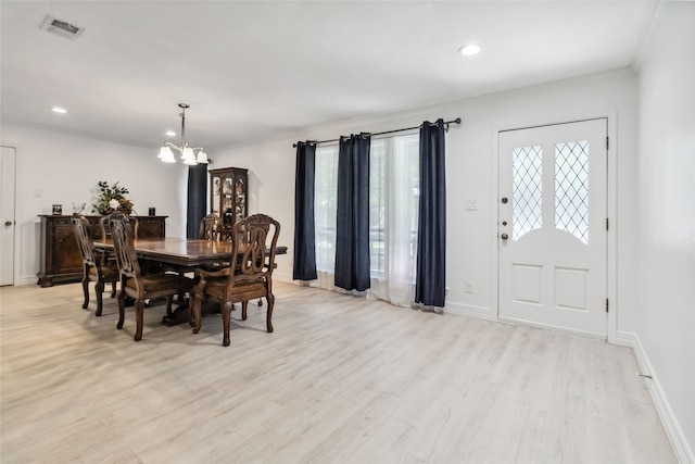 dining area featuring light hardwood / wood-style flooring, ornamental molding, and a notable chandelier