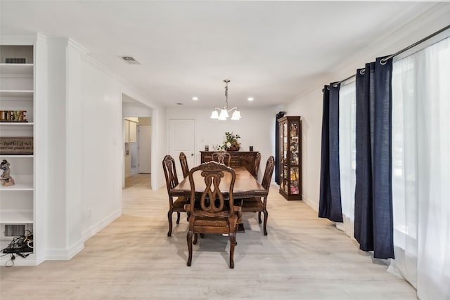 dining space featuring light hardwood / wood-style flooring, ornamental molding, and a notable chandelier