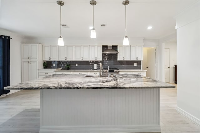 kitchen featuring light stone countertops, tasteful backsplash, wall chimney exhaust hood, pendant lighting, and a large island