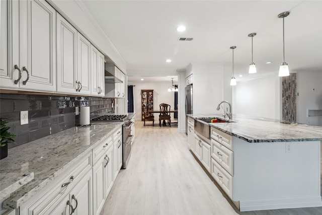 kitchen with white cabinetry, sink, hanging light fixtures, stainless steel appliances, and light stone counters