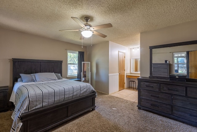 carpeted bedroom featuring ceiling fan, a textured ceiling, and multiple windows