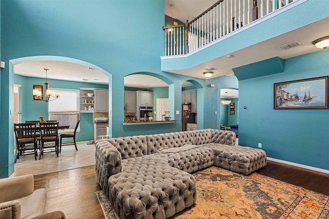 living room with a high ceiling, an inviting chandelier, and light hardwood / wood-style flooring