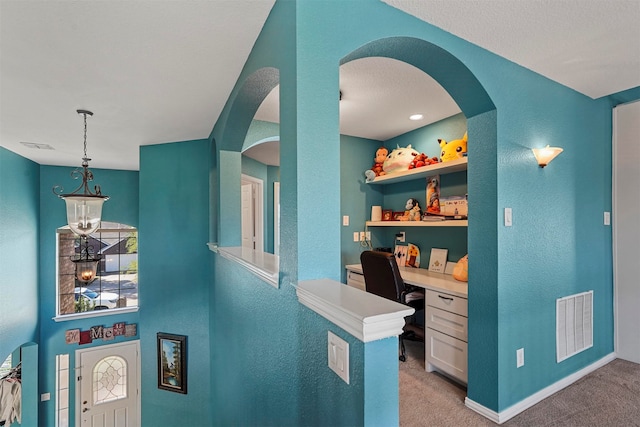 carpeted home office featuring built in desk and a notable chandelier