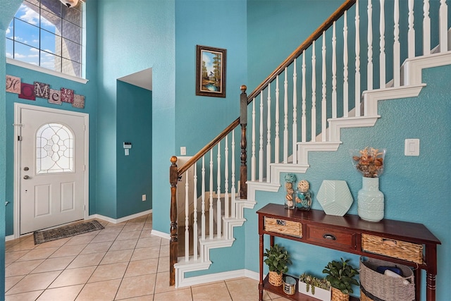 tiled entryway with a towering ceiling and a healthy amount of sunlight