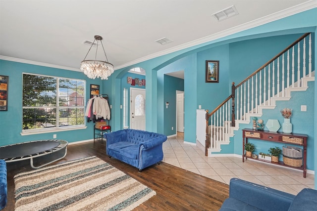 living room featuring an inviting chandelier, hardwood / wood-style floors, and crown molding