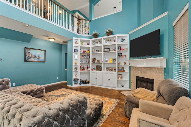 living room featuring high vaulted ceiling, a tile fireplace, and hardwood / wood-style flooring