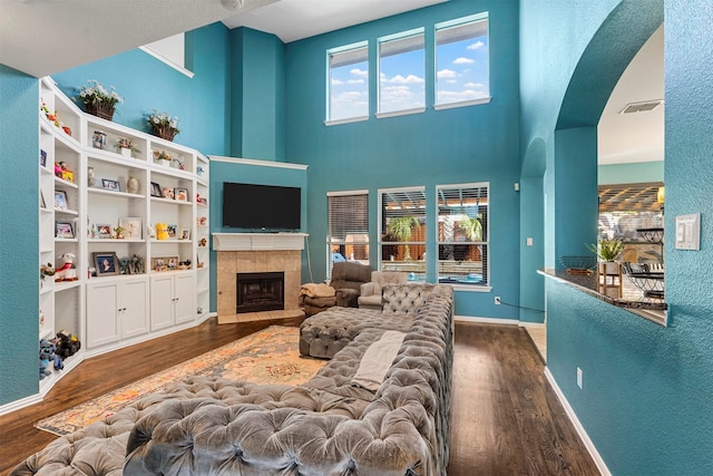 living room with dark hardwood / wood-style flooring, a tiled fireplace, and a wealth of natural light