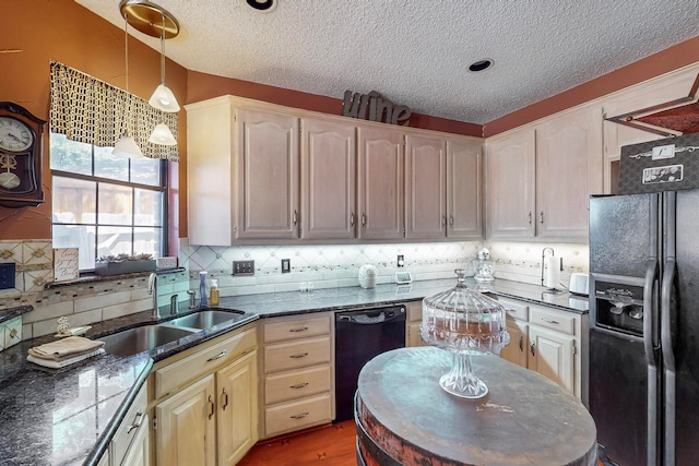 kitchen with a textured ceiling, black appliances, dark stone counters, hardwood / wood-style floors, and sink