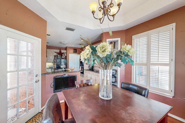 dining area featuring an inviting chandelier, a raised ceiling, and plenty of natural light