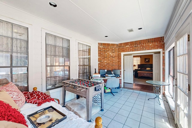 game room with brick wall and light tile patterned floors