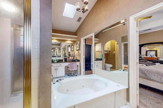 bathroom featuring lofted ceiling with skylight, vanity, toilet, and a washtub