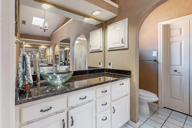 bathroom with lofted ceiling, tile patterned flooring, vanity, and toilet