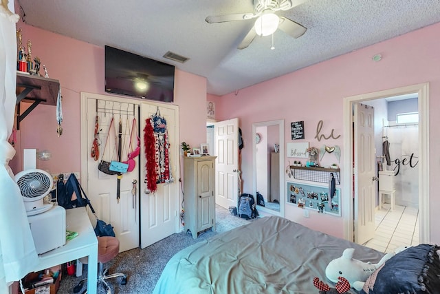 carpeted bedroom featuring ensuite bath, ceiling fan, and a textured ceiling