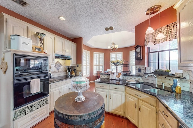 kitchen with sink, a notable chandelier, hanging light fixtures, light hardwood / wood-style flooring, and black appliances