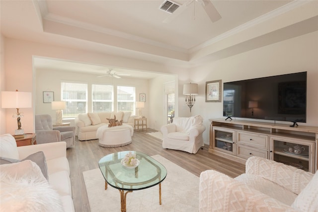 living room with a tray ceiling, light hardwood / wood-style flooring, and ceiling fan