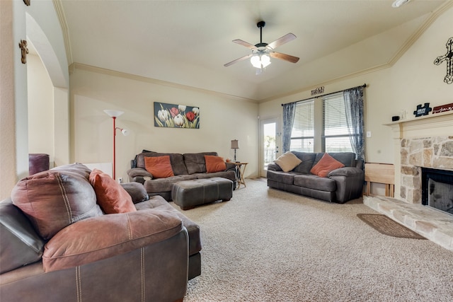 living room with ornamental molding, carpet, ceiling fan, and a stone fireplace