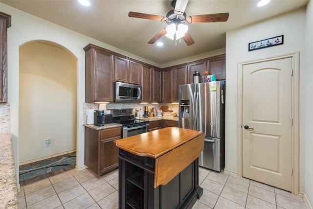 kitchen featuring light tile patterned flooring, tasteful backsplash, stainless steel appliances, dark brown cabinetry, and ceiling fan