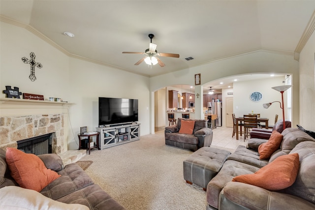 living room with ceiling fan, light colored carpet, a fireplace, crown molding, and vaulted ceiling