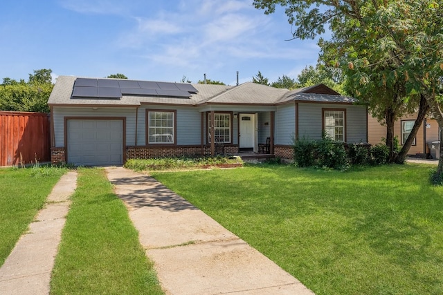 view of front of house with a front yard, a garage, solar panels, and covered porch