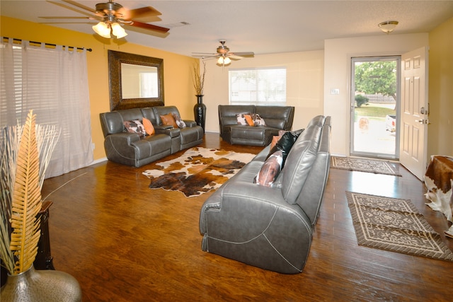 living room with a textured ceiling, dark wood-type flooring, and ceiling fan