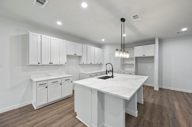 kitchen featuring white cabinetry, a center island with sink, decorative light fixtures, and sink