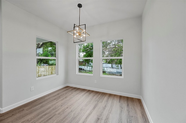 empty room featuring an inviting chandelier and hardwood / wood-style flooring