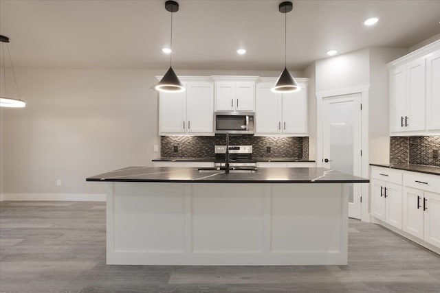 kitchen with sink, appliances with stainless steel finishes, hanging light fixtures, and light wood-type flooring