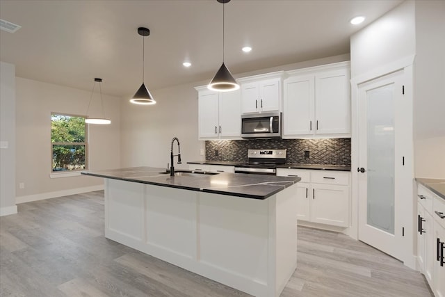 kitchen with light hardwood / wood-style flooring, stainless steel appliances, a center island with sink, decorative light fixtures, and white cabinets