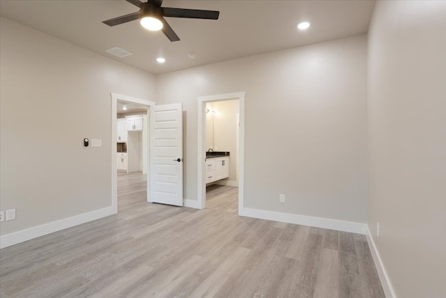 unfurnished bedroom featuring connected bathroom, ceiling fan, and light wood-type flooring