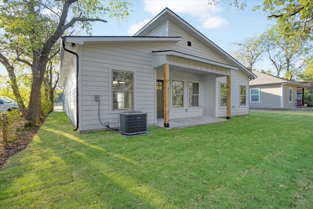 rear view of property with central air condition unit and a lawn