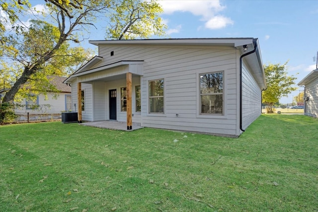 rear view of property with cooling unit and a lawn