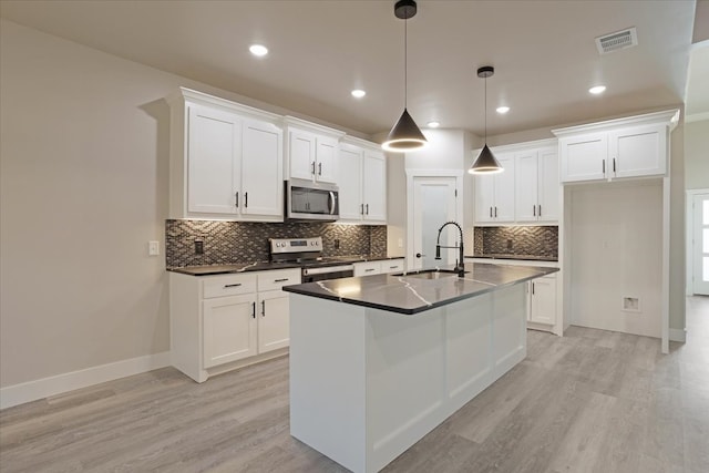 kitchen with stainless steel appliances, a center island with sink, sink, white cabinetry, and light hardwood / wood-style floors