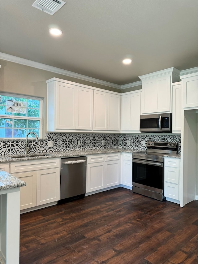 kitchen featuring dark hardwood / wood-style flooring, stainless steel appliances, white cabinets, crown molding, and decorative backsplash