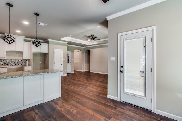 kitchen with tasteful backsplash, light stone countertops, hanging light fixtures, white cabinets, and dark hardwood / wood-style floors