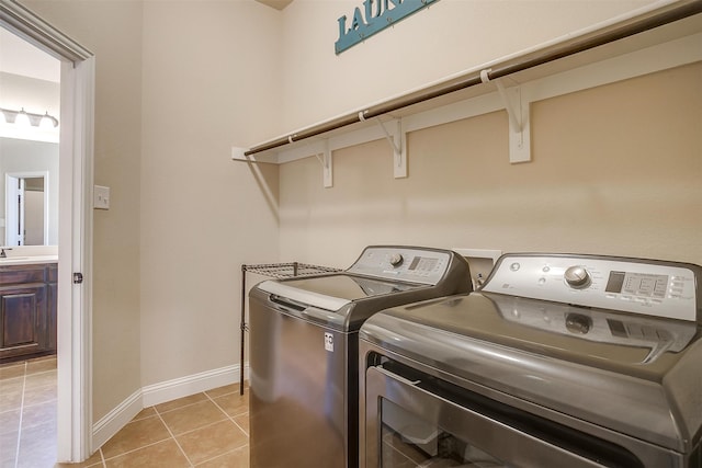 clothes washing area featuring separate washer and dryer, sink, and light tile patterned floors