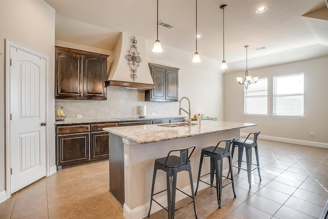 kitchen featuring a breakfast bar area, a kitchen island with sink, sink, and a notable chandelier