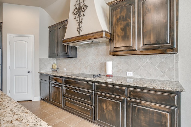 kitchen featuring light stone counters, custom exhaust hood, backsplash, and black electric stovetop