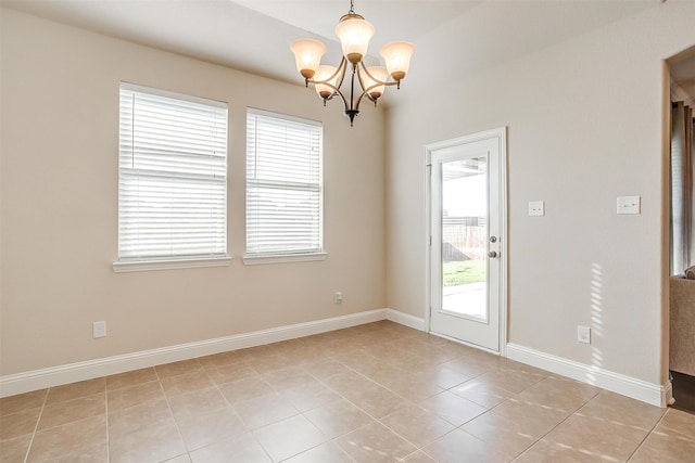 tiled spare room featuring a chandelier and a healthy amount of sunlight