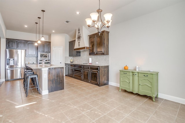 kitchen with dark brown cabinetry, pendant lighting, an island with sink, a chandelier, and stainless steel appliances