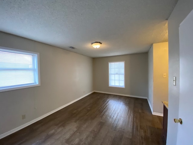 empty room with a textured ceiling and dark wood-type flooring