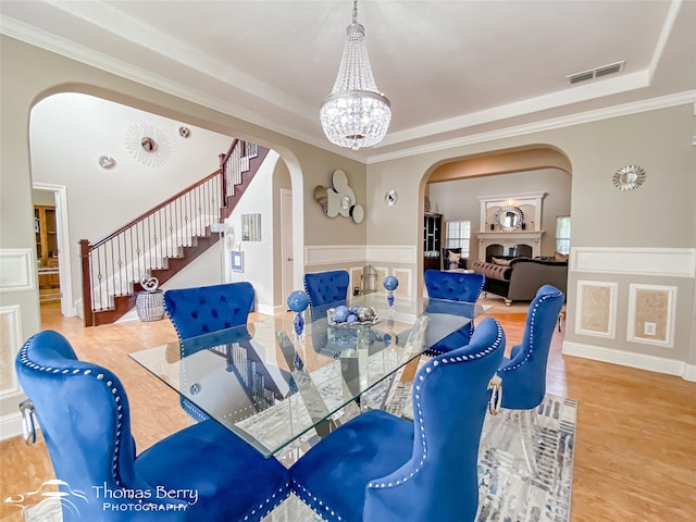 dining area featuring crown molding, a tray ceiling, hardwood / wood-style floors, and a chandelier